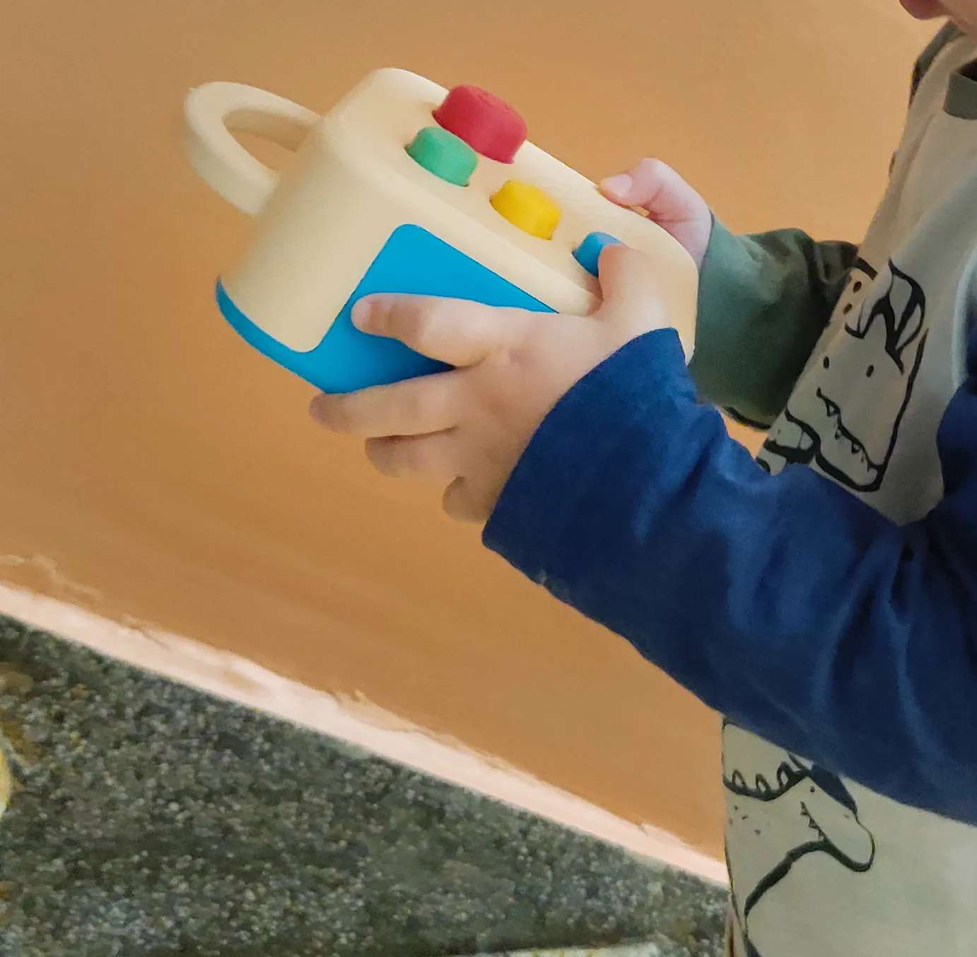 A child's hands holding a cream and blue Koobiba