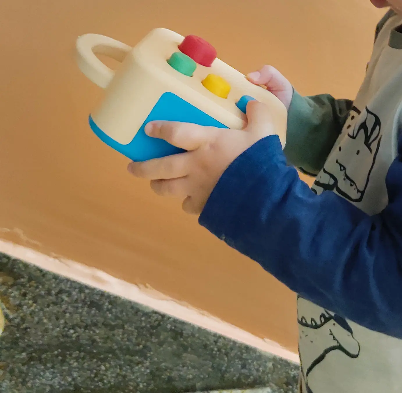 A child's hands holding a cream and blue Koobiba
